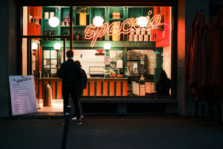 a couple looking in a pizza shop window at night