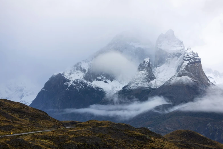 clouds hover above the snow - capped mountains in the valley