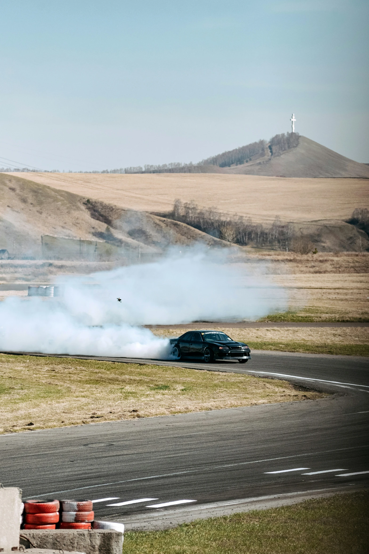 a car is driving on a paved road and the smoke is emitting from it