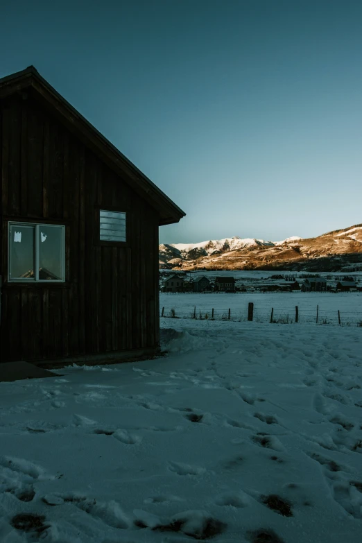 a wooden house in a field covered with snow