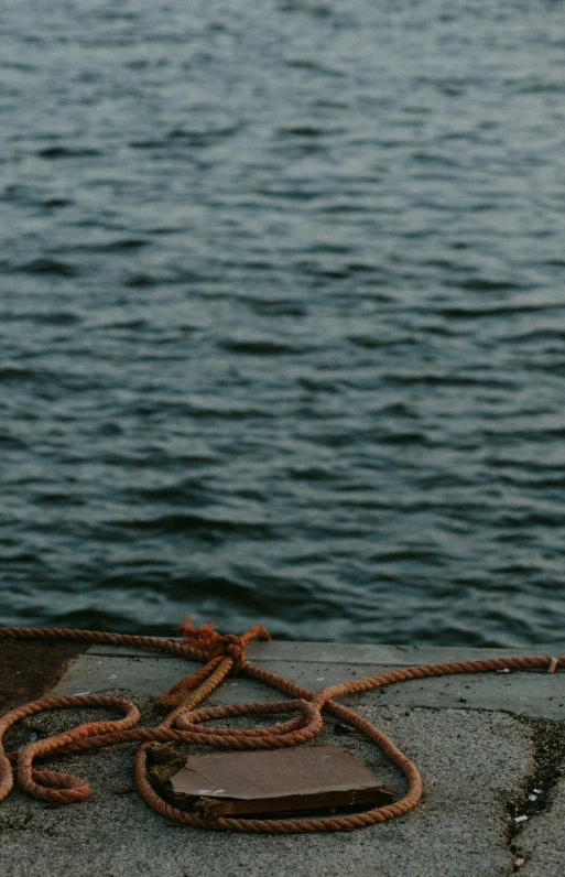 a rope on top of a concrete wall by a body of water