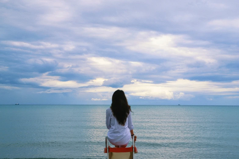 a person sitting on a bench next to the ocean