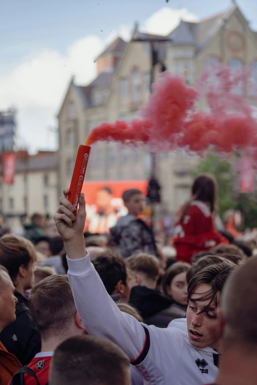 a crowd of people gathered around and holding up red smoke