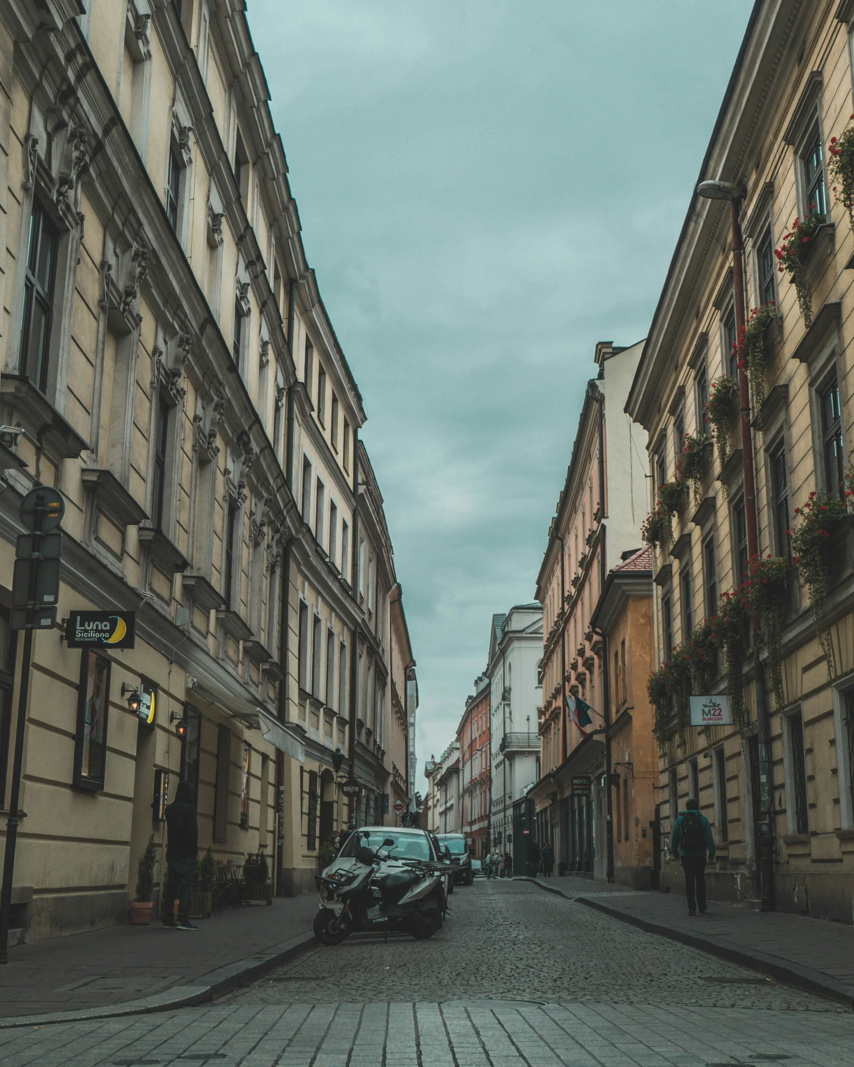 an old street is empty and crowded with parked cars