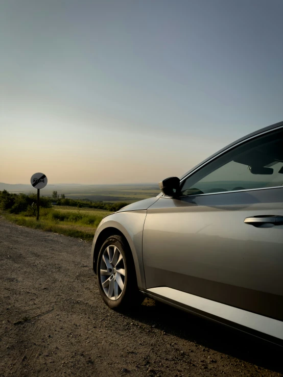 a grey car is parked on the side of a rural road