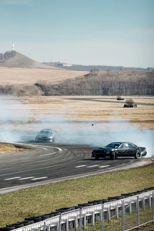 two cars that are on a road near a grass covered field