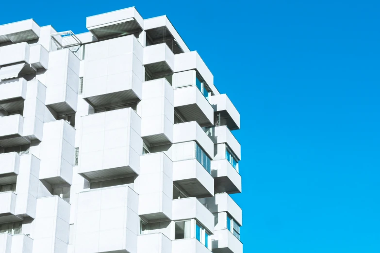 a white building with balconies on it against a blue sky