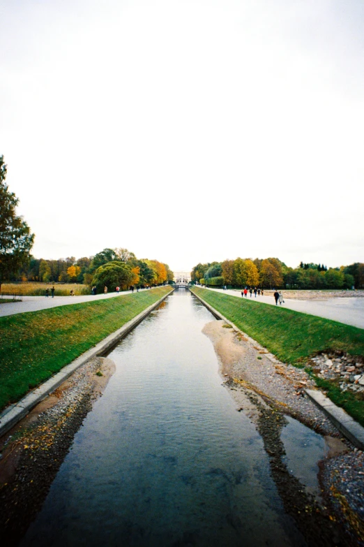 people walking along the water way in a large park