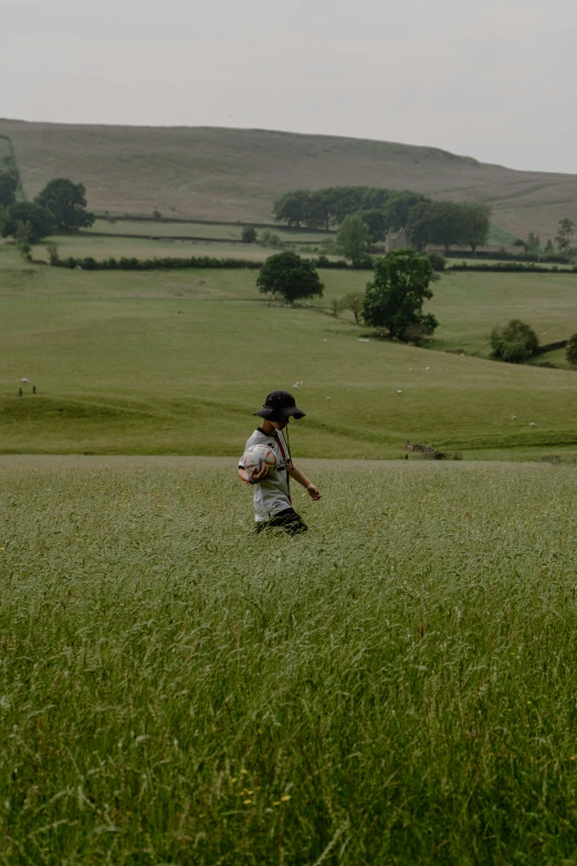 a person in a field with trees and hills behind them