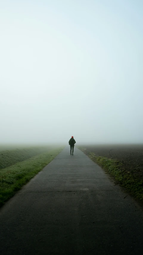 the person is walking down the road in the fog