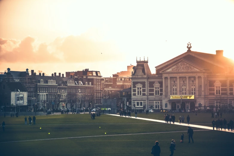 many people on the grassy field and a very old building in the background