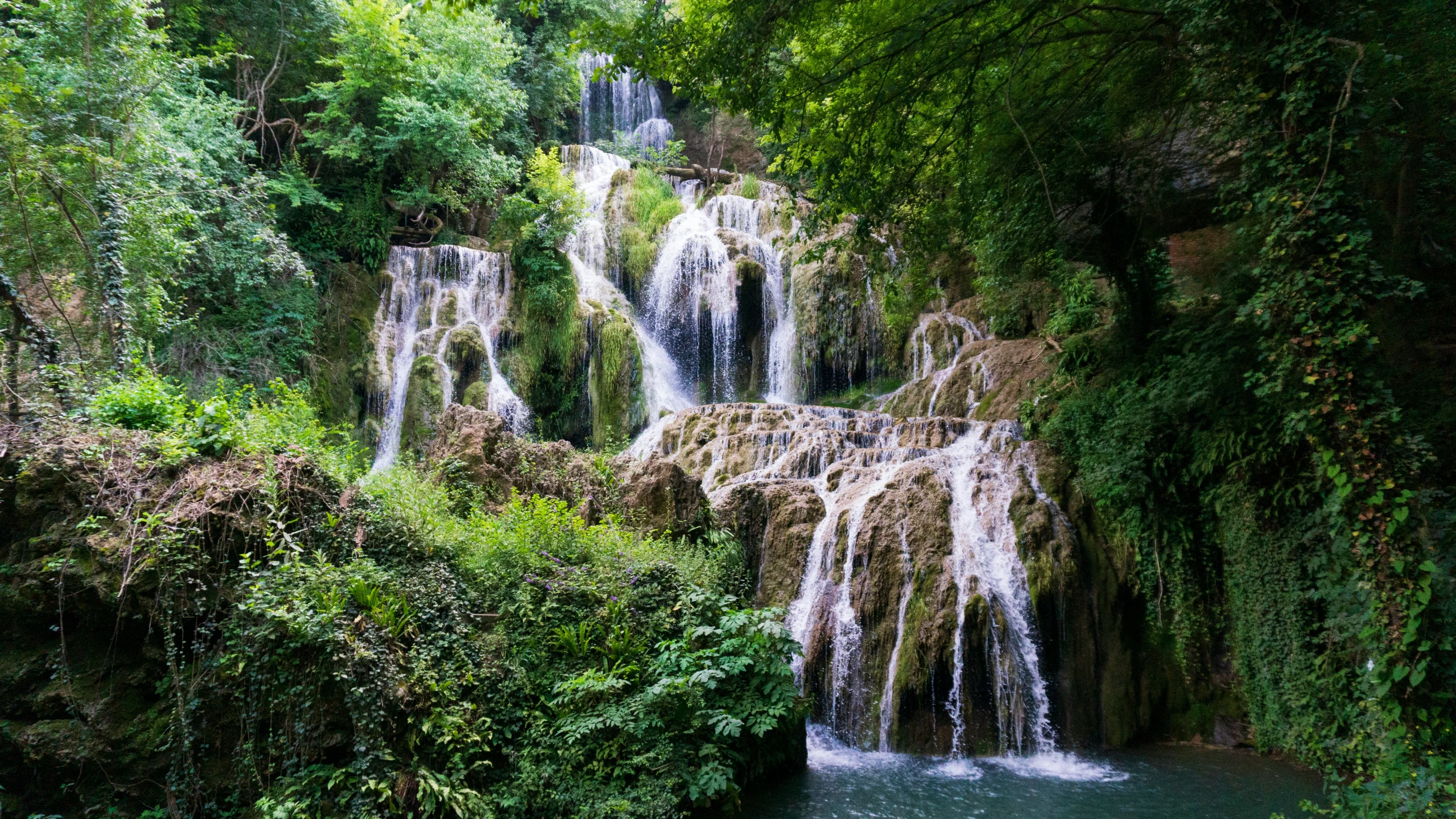 a waterfall with lots of water and green foliage