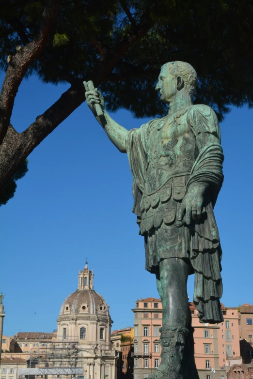 the statue stands next to the large tree