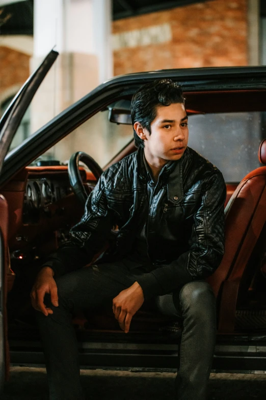 man sitting in back seat of old red convertible vehicle