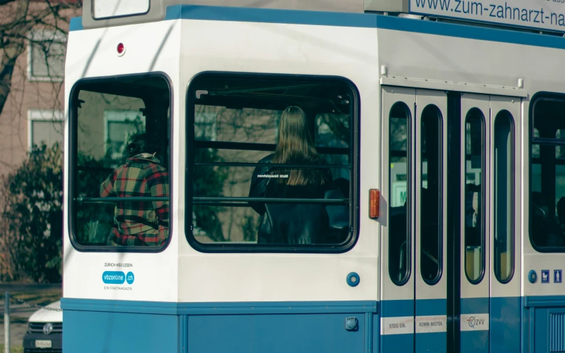 a white and blue city bus with a girl driving