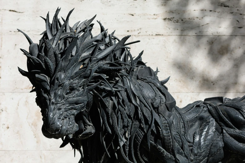 a black statue of a dragon is against a white wall