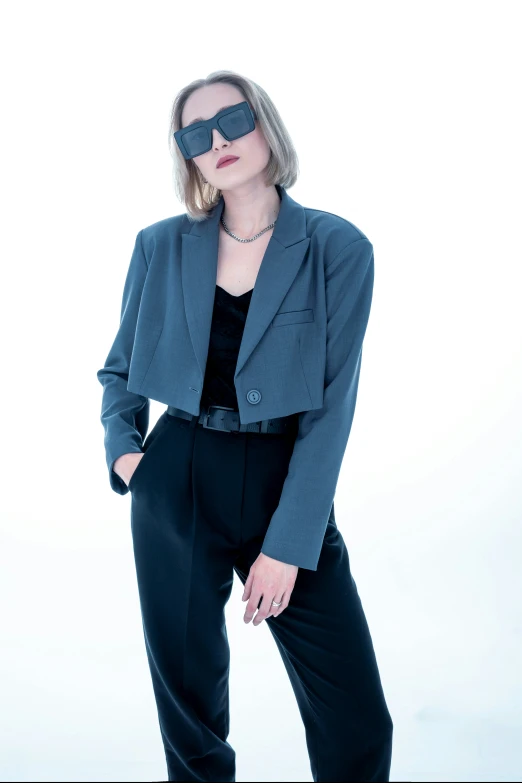 a woman in business attire and sunglasses posing
