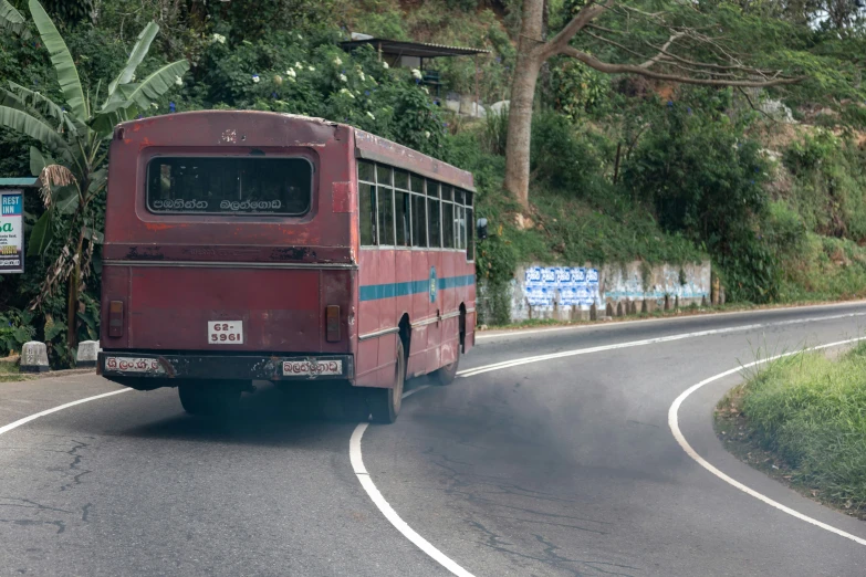 a large red bus driving down a curvy road