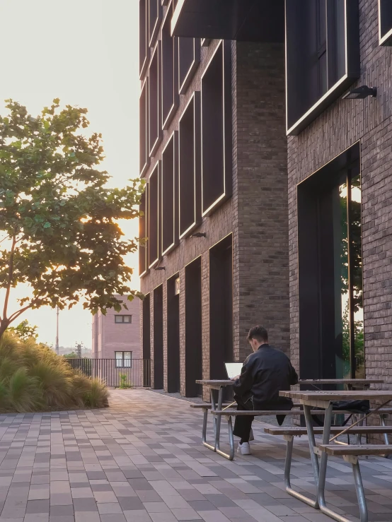 two people are sitting on benches working on their laptops