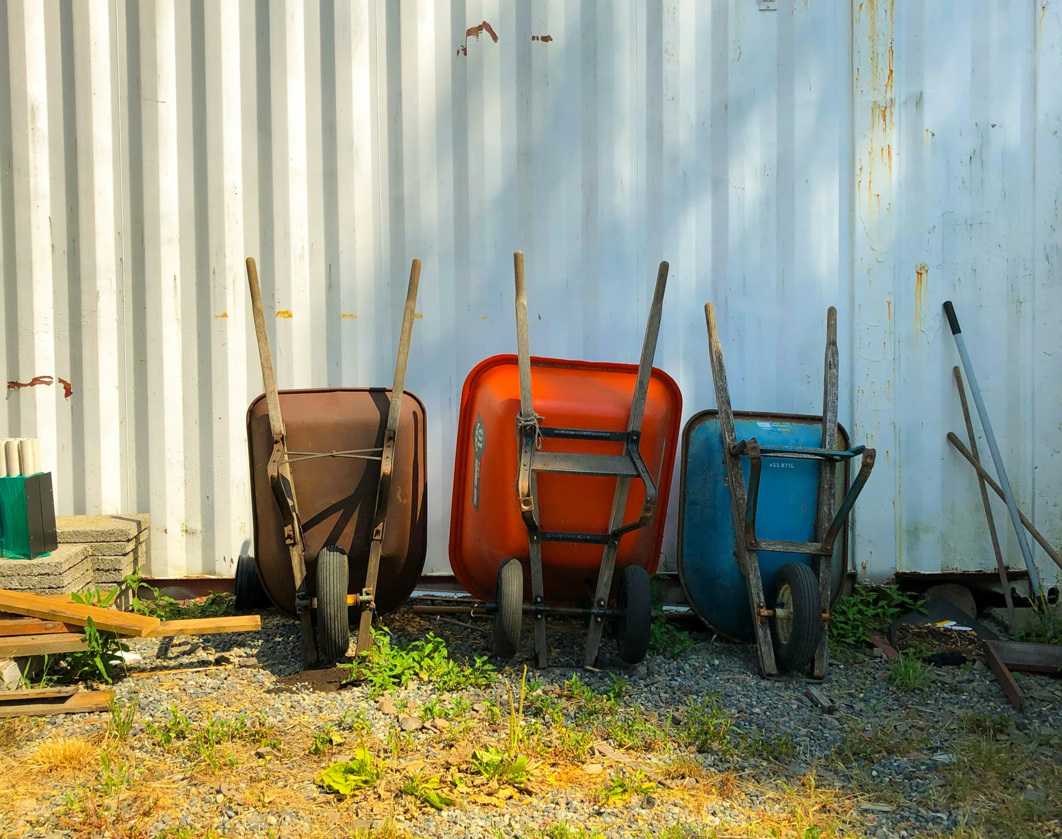 five empty luggage bags and four different chairs against a white wall