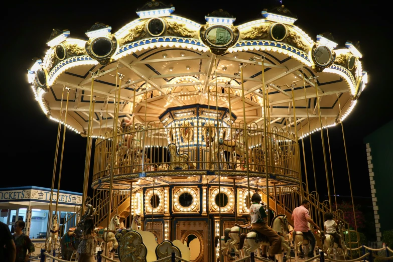 several people riding on horses next to a lit carousel