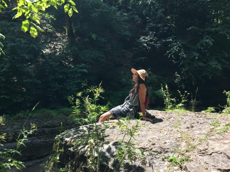 a woman sitting on a rock in a forest