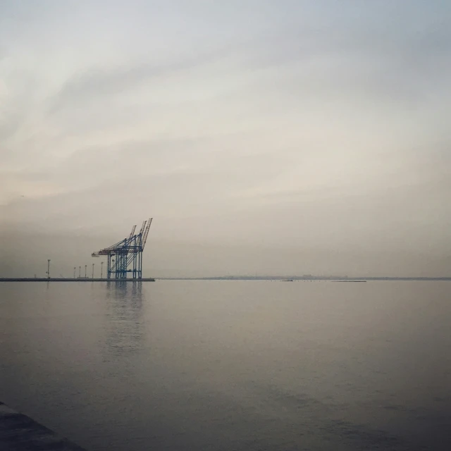 an empty harbor with some cranes in the background