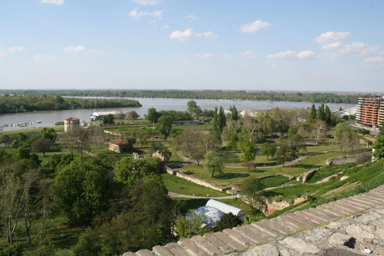 a green park by a river is seen from above