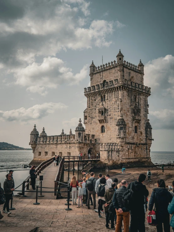 people standing around in front of a castle with water