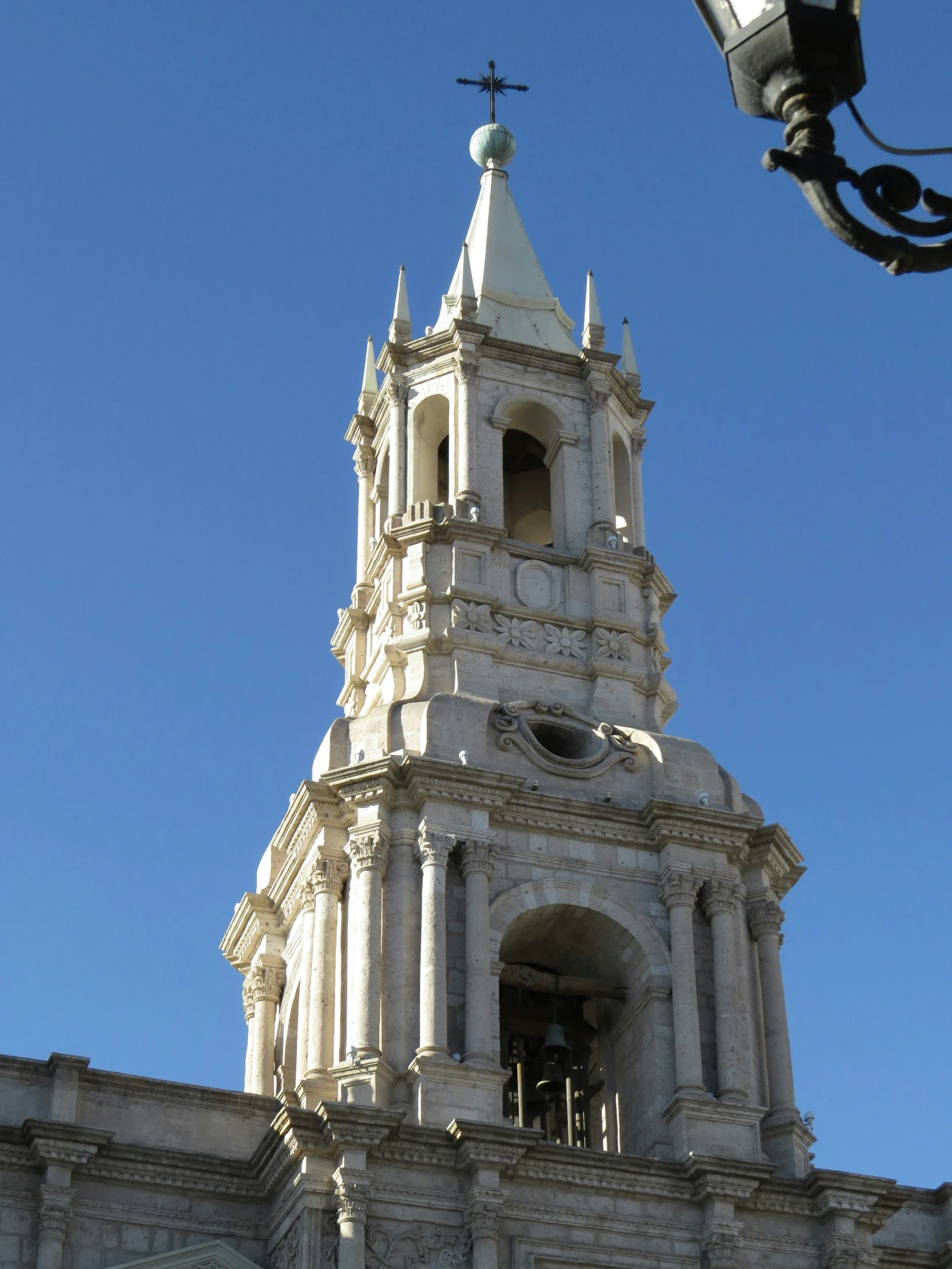 a white clock tower with a steeple and cross at the top