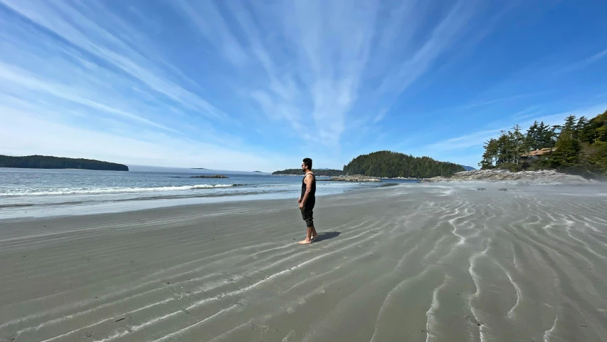 a man is standing on the beach by the water