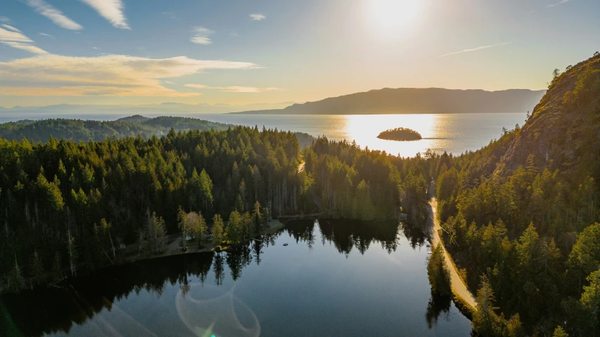 a lake in the middle of trees and mountains with the sun shining over it