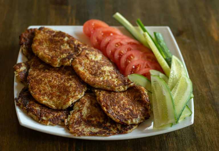 a meal on a plate includes carrots, celery and sliced tomato