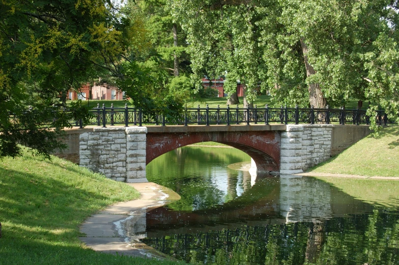 a bridge over water surrounded by trees and grass