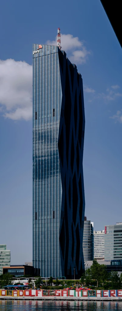 a tall building next to a river with the city in the background