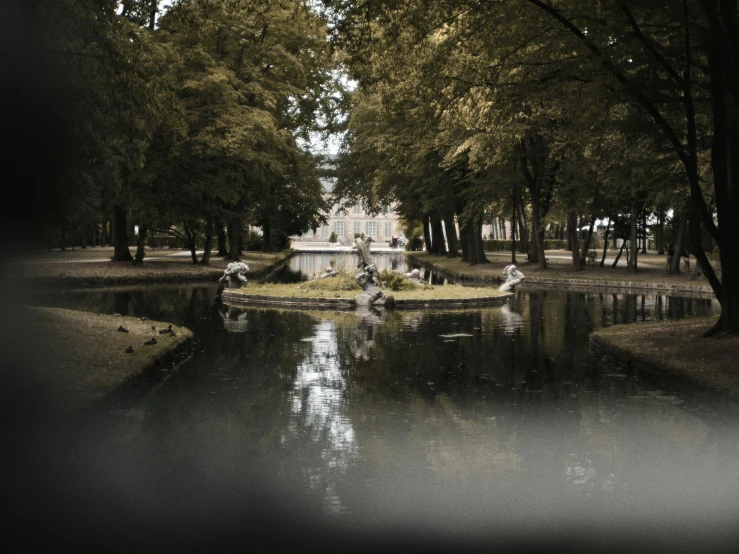 an ancient fountain on the lake surrounded by trees