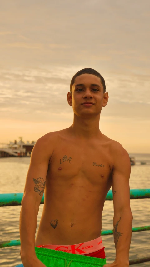 young shirtless man standing outside near body of water