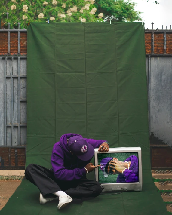 a man kneeling down next to a tv with the image of a baseball player on it