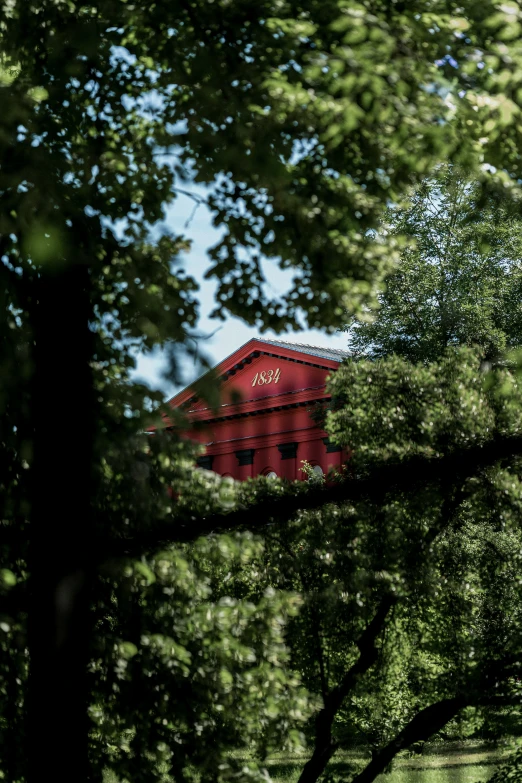 a red building with a clock tower surrounded by trees