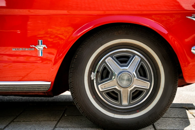 the wheel of an old mustang muscle car with chrome finish