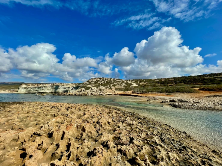 the beach with blue sky and clouds near the sand