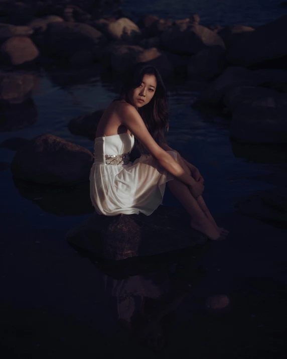 a young woman sitting in the water at night