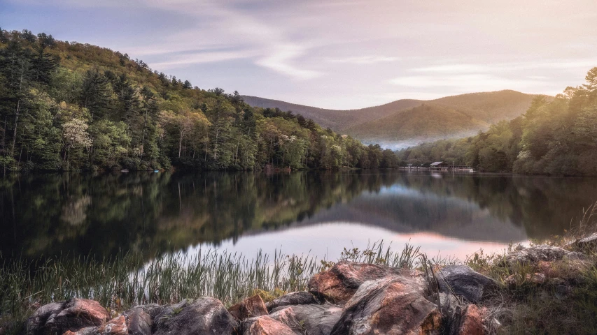 a lake surrounded by mountains with many rocks and trees