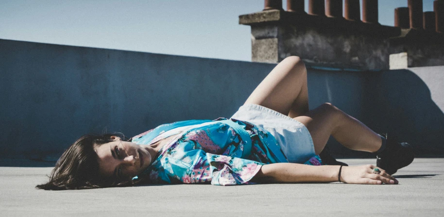 a woman laying on her side on the ground wearing a shirt and skirt