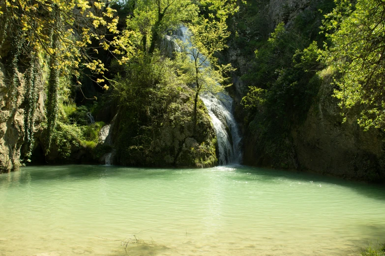 the water is green as it flows from a small waterfall