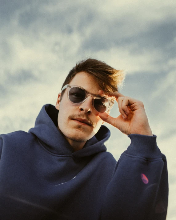 a man standing with his hand on his forehead wearing sunglasses