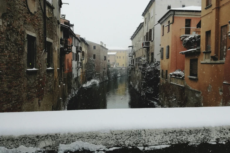 a narrow river flowing through a snow covered alley