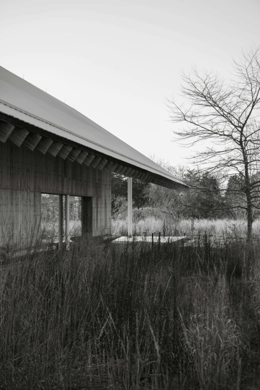 an empty barn sitting by some water and some trees