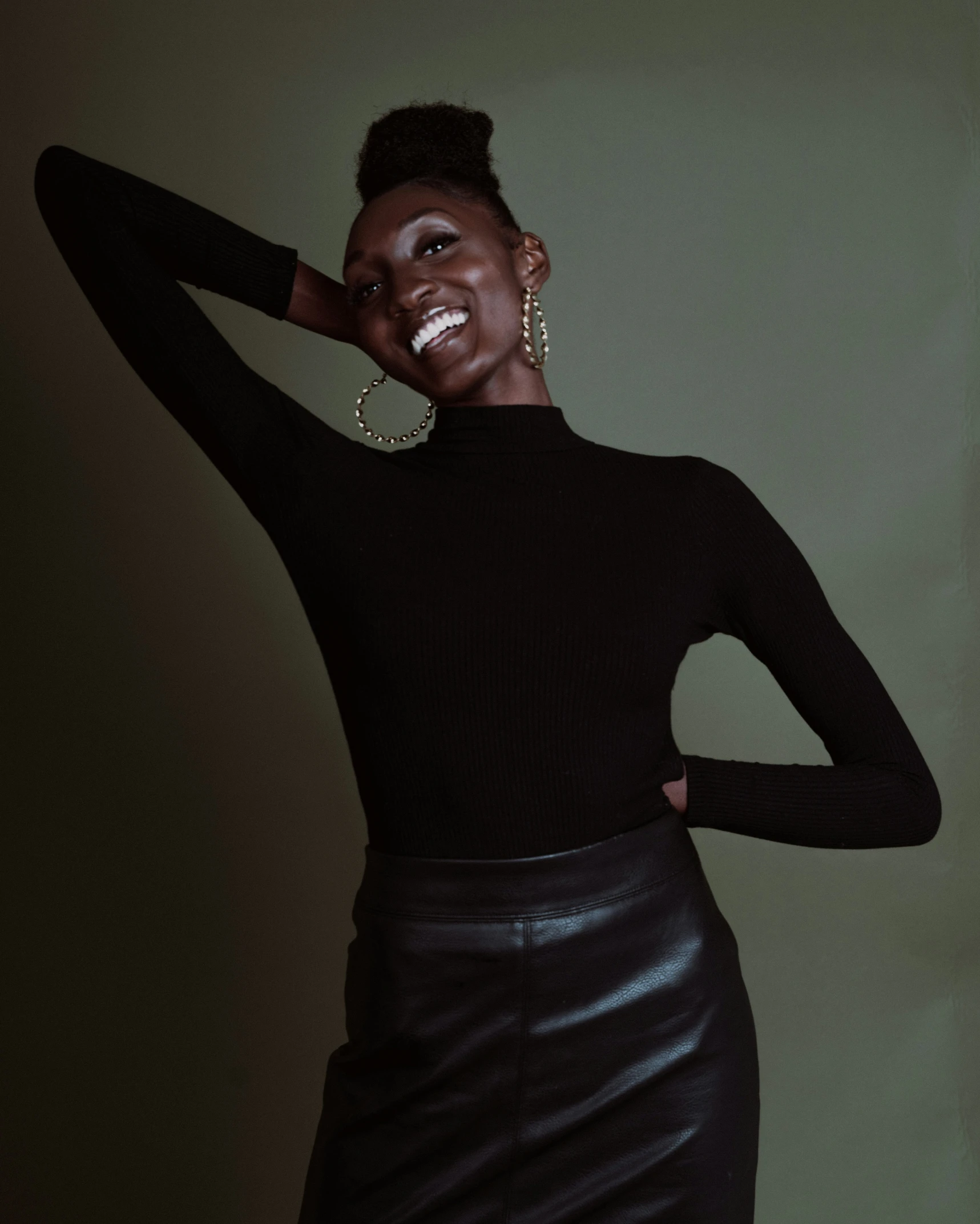 a woman smiling wearing a black shirt and leather skirt