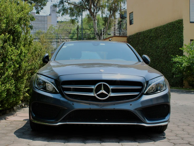 a mercedes cla sits parked in front of some shrubs